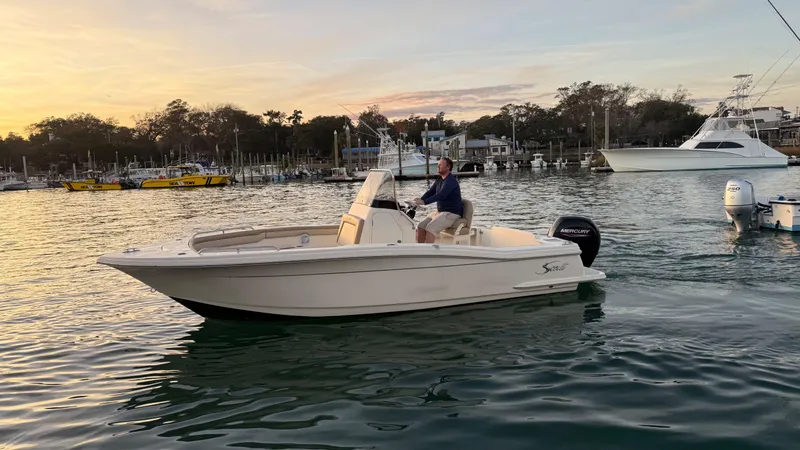 Slide: The Image of 2021 Scout 215 XSF boat cruising on a calm lake at sunset. - 6