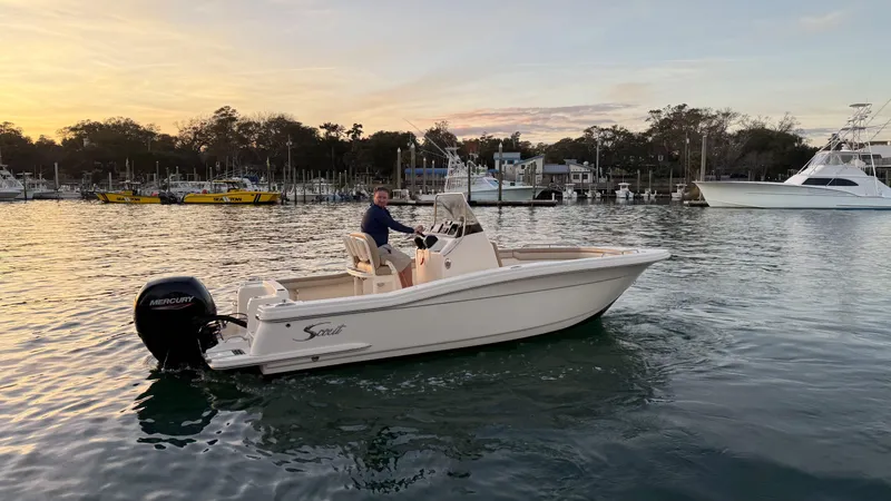 Slide: The Image of 2021 Scout 215 XSF boat cruising on a calm lake at sunset. - 7