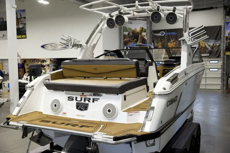 Slide: The Image of 2024 Cobalt R4 Surf boat in showroom, rear view with speakers and surfboard racks. - 8