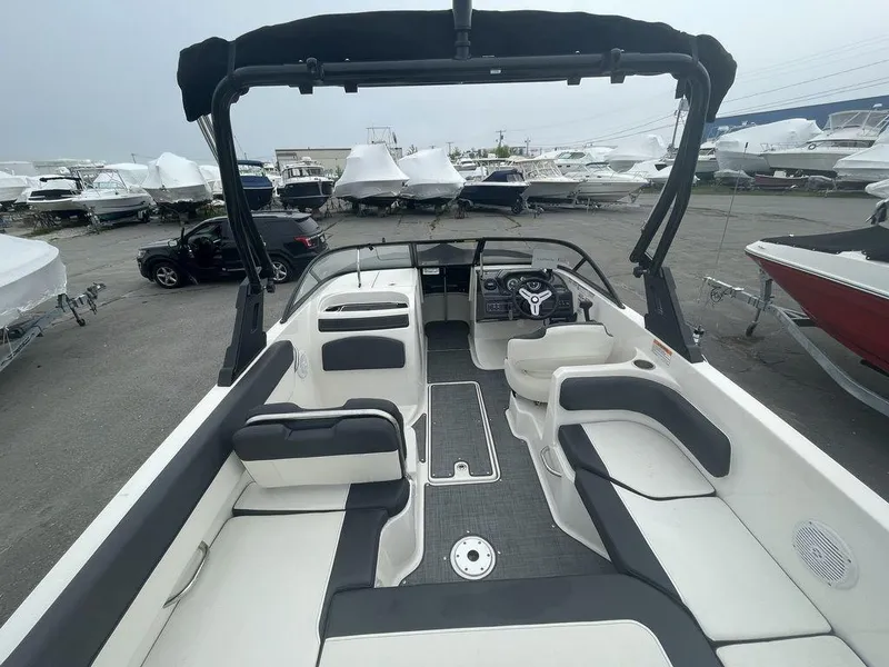 Slide: The Image of 2021 Bayliner VR6 OB boat interior with seating and steering wheel, parked in a marina. - 8
