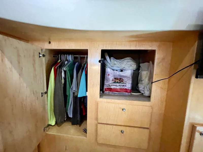 Slide: The Image of Wooden closet with hanging clothes and storage shelves in a 1999 Californian 39 boat. - 27