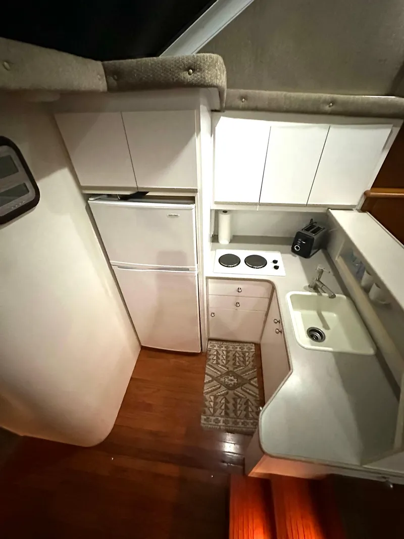 Slide: The Image of 1995 Silverton AFT CABIN kitchen with white cabinets, fridge, stove, and sink. - 5