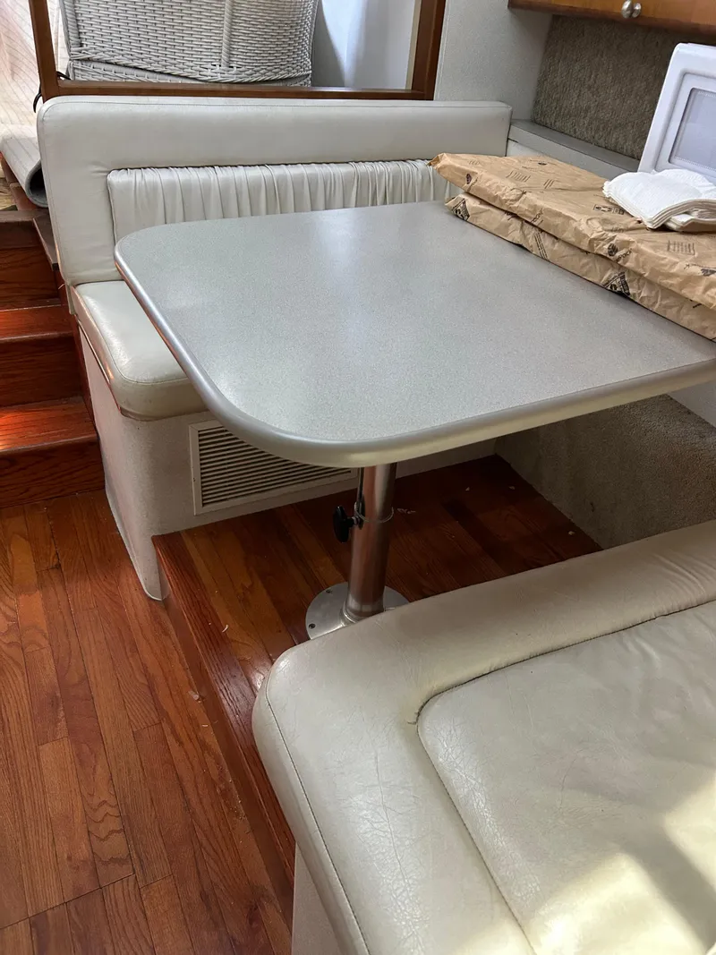 Slide: The Image of 1995 Silverton AFT CABIN interior with dining area, wooden flooring, and cushioned seating. - 19