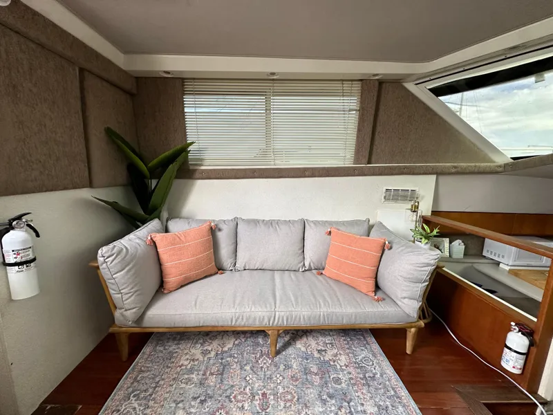 Slide: The Image of 1995 Silverton AFT CABIN interior with gray sofa, orange pillows, and decorative plants. - 4
