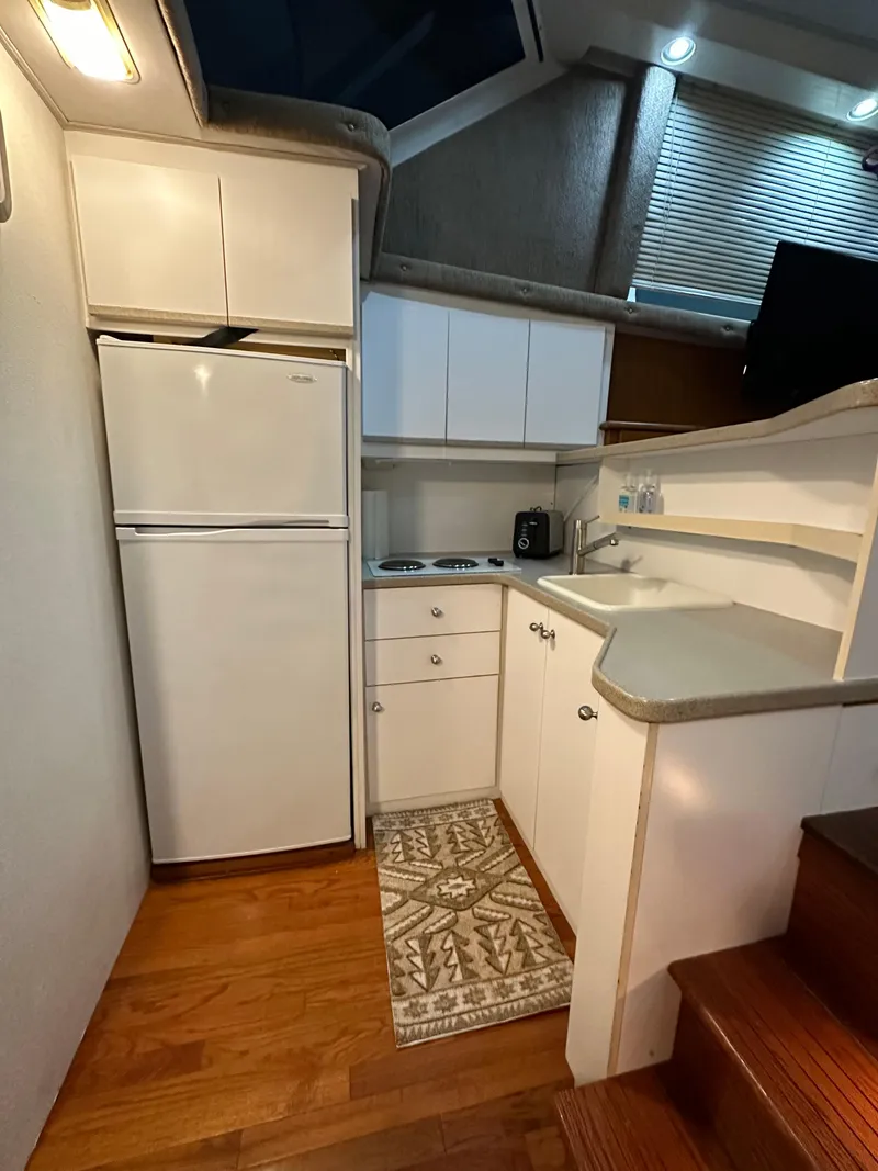 Slide: The Image of 1995 Silverton AFT CABIN kitchen with white cabinets, fridge, and wooden flooring. - 7