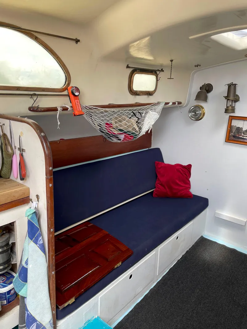 Slide: The Image of Interior of 1960 Rhodes Bounty II sailboat with blue seating and nautical decor. - 13