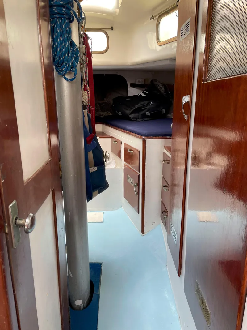 Slide: The Image of Interior of 1960 Rhodes Bounty II sailboat with wooden cabinetry and blue flooring. - 16