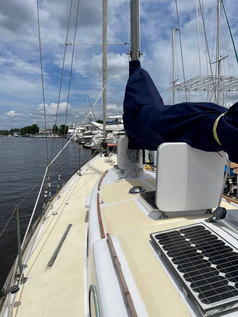 Slide: The Image of 1960 Rhodes Bounty II sailboat deck with solar panel, docked at marina under cloudy sky. - 19