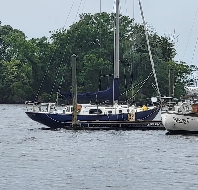 Slide: The Image of Sailboat docked on a calm river, surrounded by lush greenery, Rhodes Bounty II, 1960 model. - 2