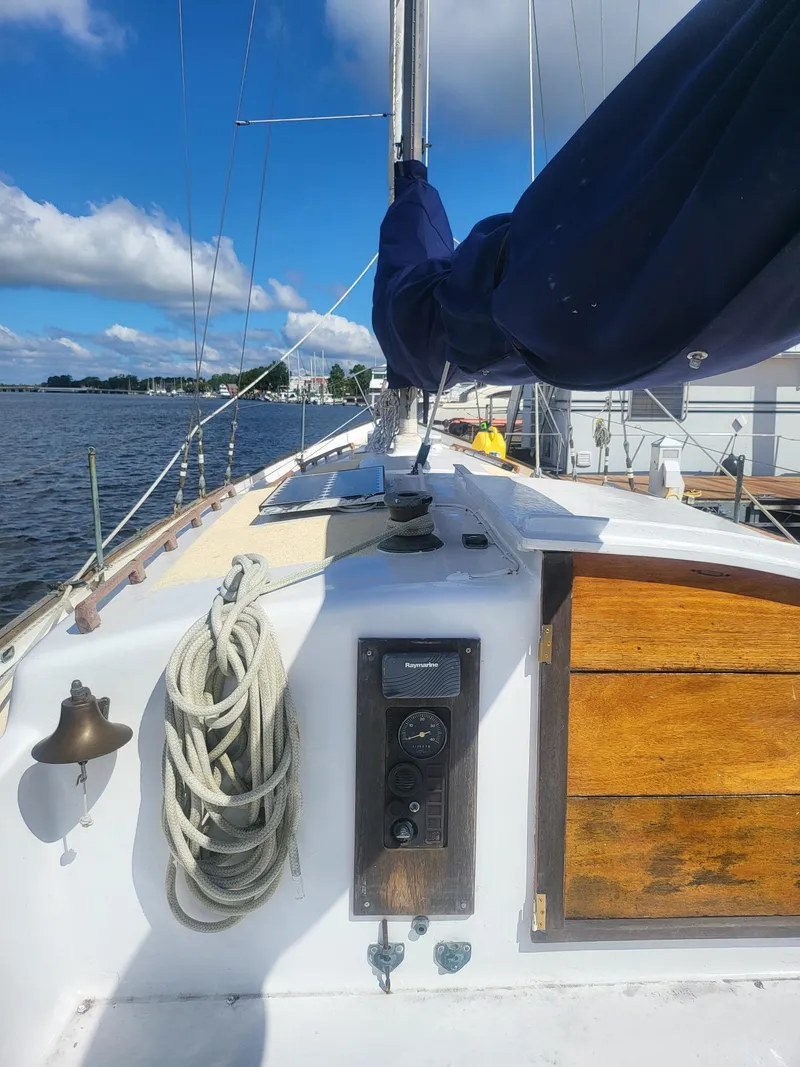 Slide: The Image of 1960 Rhodes Bounty II sailboat deck with ropes and wooden details under a clear sky. - 6