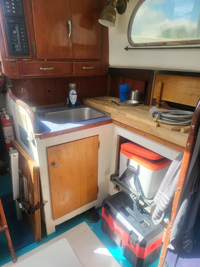 Slide: The Image of 1960 Rhodes Bounty II yacht kitchen with wooden cabinets, sink, and storage. - 7