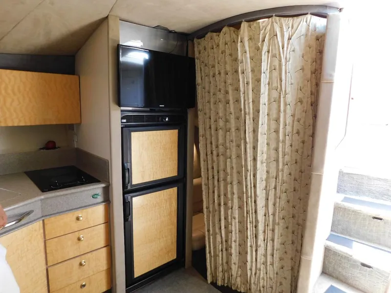 Slide: The Image of 1999 Formula 41 Performance Cruiser interior with kitchenette, fridge, TV, and privacy curtain. - 31
