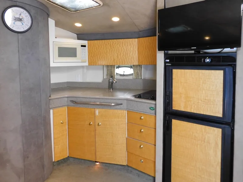 Slide: The Image of 1999 Formula 41 Performance Cruiser kitchen with microwave, fridge, TV, and wooden cabinets. - 34