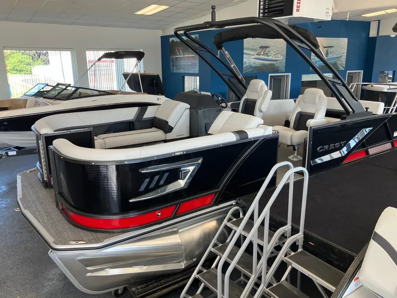Slide: The Image of 2024 Crest Caribbean 230 SLS RS pontoon boat in showroom, featuring sleek black and white design. - 6