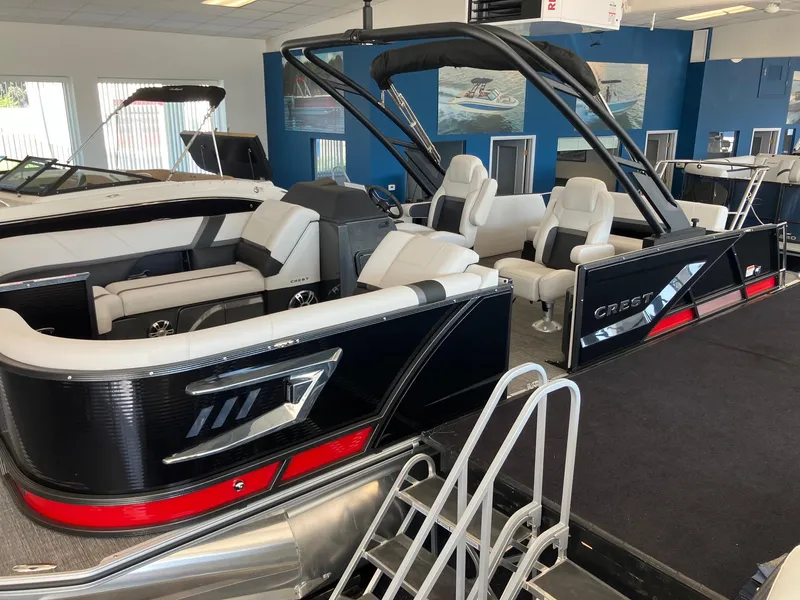 Slide: The Image of 2024 Crest Caribbean 230 SLS RS pontoon boat in showroom, featuring luxurious seating and modern design. - 7