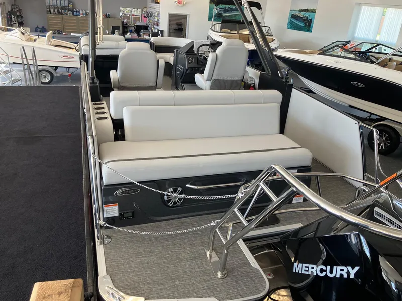 Slide: The Image of 2024 Crest Caribbean 230 SLS RS pontoon boat interior with white seating and Mercury engine. - 9