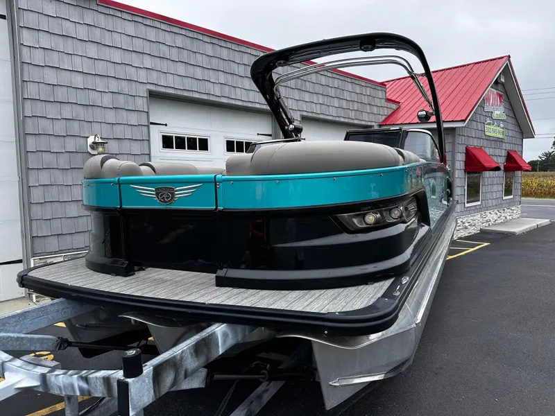 Slide: The Image of 2021 Avalon Excalibur 2585 Windshield Elite Tri Toon boat, teal and black, parked outside dealership. - 3
