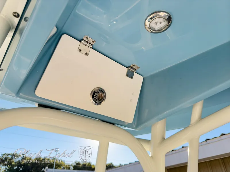 Slide: The Image of 2024 Pathfinder TRS 2200 boat compartment with latch and gauge, under blue canopy. - 26