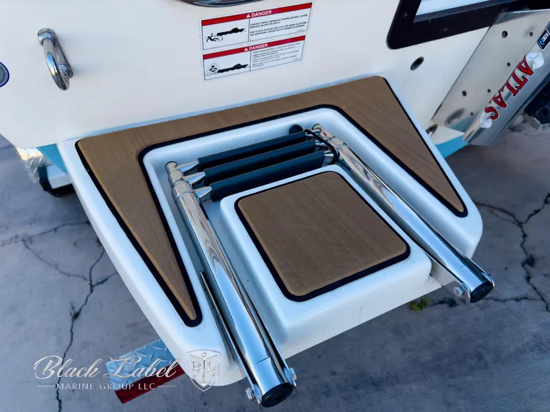 Slide: The Image of 2024 Pathfinder TRS 2200 boat ladder with teak accents and safety labels. - 33