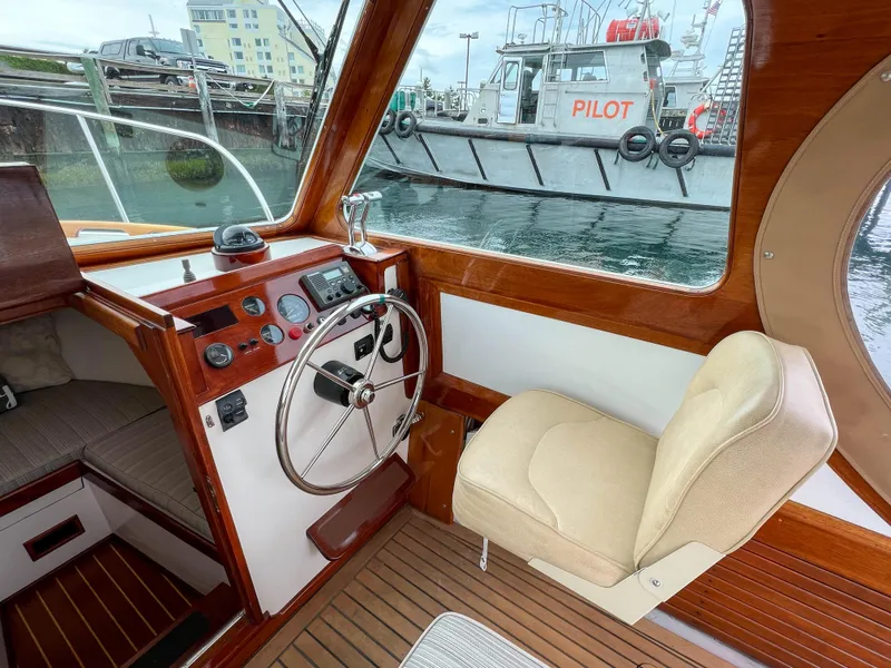 Slide: The Image of Interior of 2004 Custom Pemaquid Beach 22 boat with steering wheel and beige captain's chair. - 13