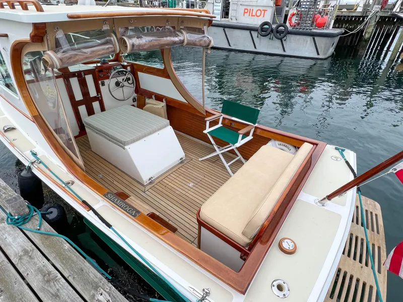 Slide: The Image of Custom 2004 Pemaquid Beach 22 boat docked, featuring a wooden deck and seating area. - 27