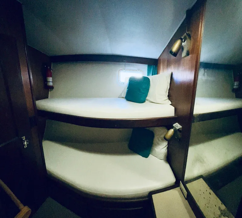 Slide: The Image of 1978 Hatteras 37 Convertible cabin with bunk beds and teal pillows. - 5