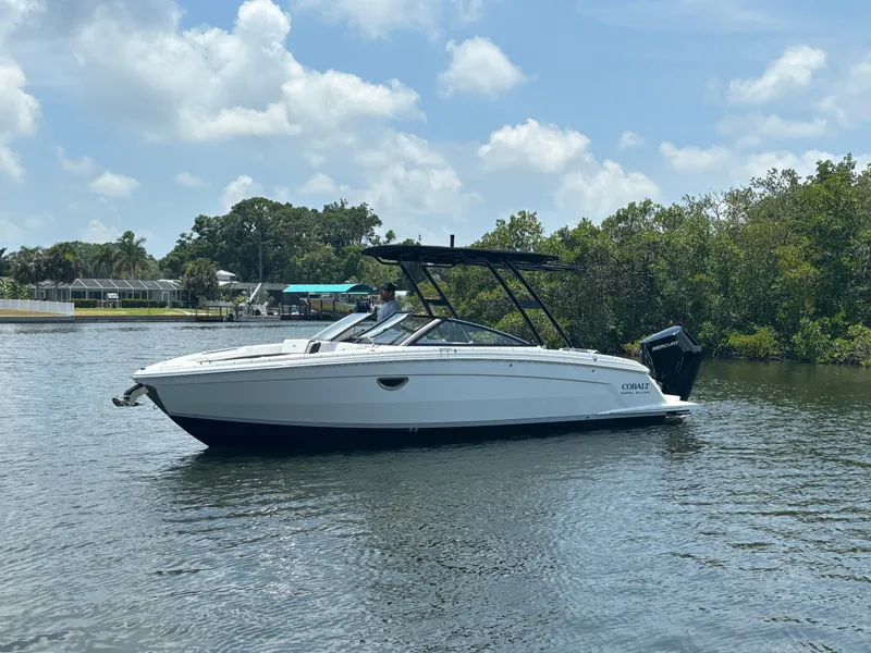 Slide: The Image of 2024 Cobalt R8 Outboard boat on a calm lake with lush greenery. - 3