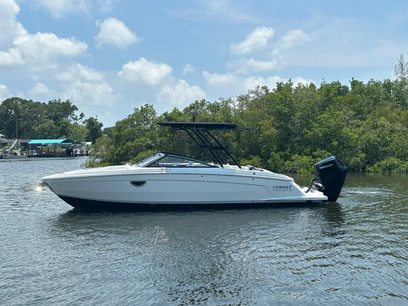 Slide: The Image of 2024 Cobalt R8 Outboard boat on a calm river with lush greenery. - 4