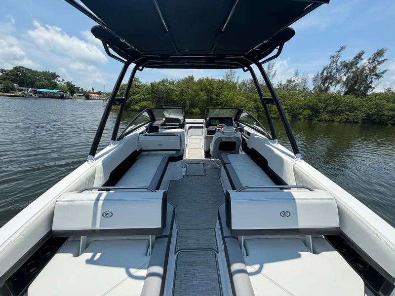 Slide: The Image of 2024 Cobalt R8 Outboard boat interior with white seating and black canopy on a calm lake. - 8