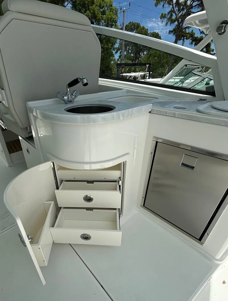 Slide: The Image of 2024 World Cat 325 DC boat interior with sink, storage drawers, and mini fridge. - 9
