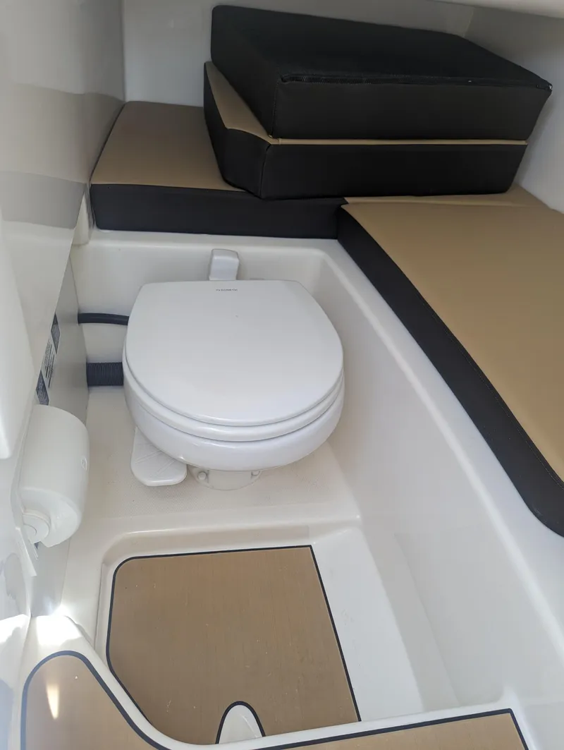Slide: The Image of 2024 Sea Ray SDX 270 boat interior with toilet and cushioned seating. - 19