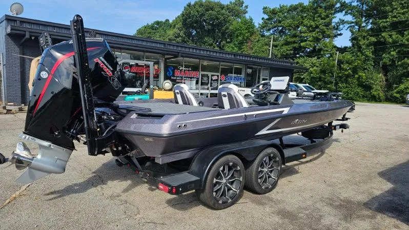 Slide: The Image of 2024 iKon LX21 boat with powerful outboard motor, parked outside a marine shop. - 2