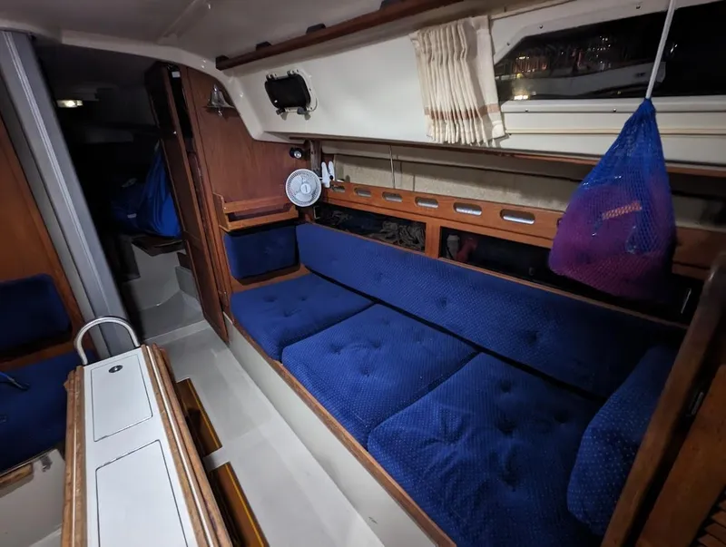 Slide: The Image of Interior of 1985 O'Day 35 sailboat with blue cushioned seating and wooden accents. - 13