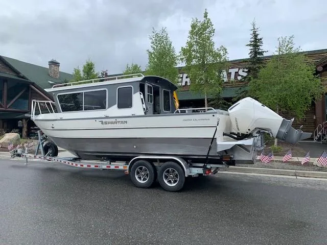 Slide: The Image of 2024 Spartan 2600 Olympia boat on trailer, parked outdoors under cloudy sky. - 2
