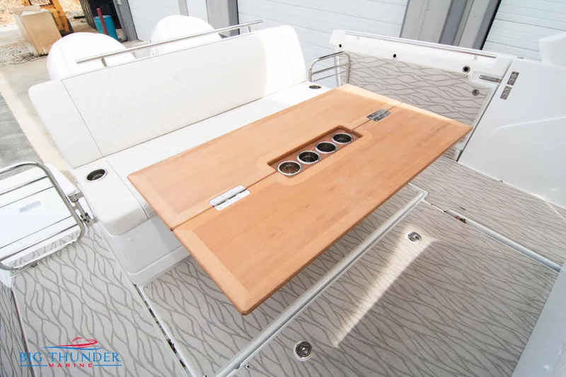 Slide: The Image of 2024 Jeanneau DB/37 OB boat interior with wooden table and cup holders. - 17