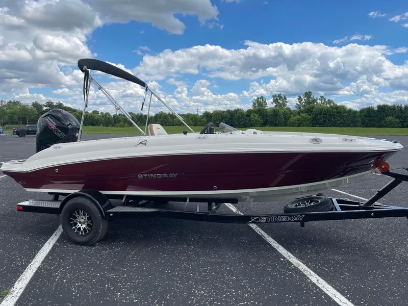 Slide: The Image of 2024 Stingray 182 SC boat on trailer, parked outdoors under a blue sky. - 2