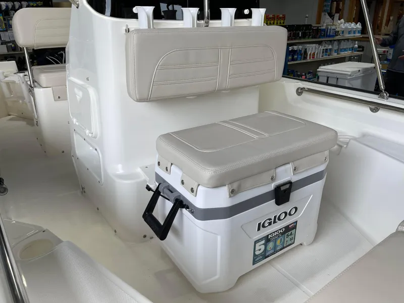 Slide: The Image of 2024 Boston Whaler 150 Montauk boat interior with Igloo cooler and cushioned seating. - 9