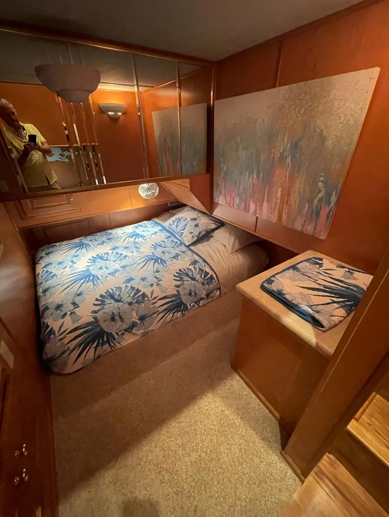 Slide: The Image of 2003 Sharpe 75' Houseboat bedroom with floral bedding and wooden interior. - 17