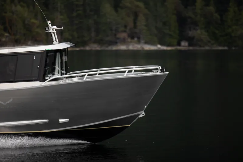 Slide: The Image of 2025 Jasper Marine Defender 22 boat cruising on a calm lake with forest background. - 19
