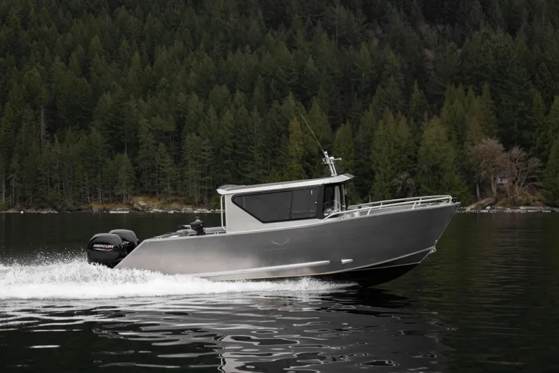 Slide: The Image of 2025 Jasper Marine Defender 22 boat cruising on a lake with forested background. - 16