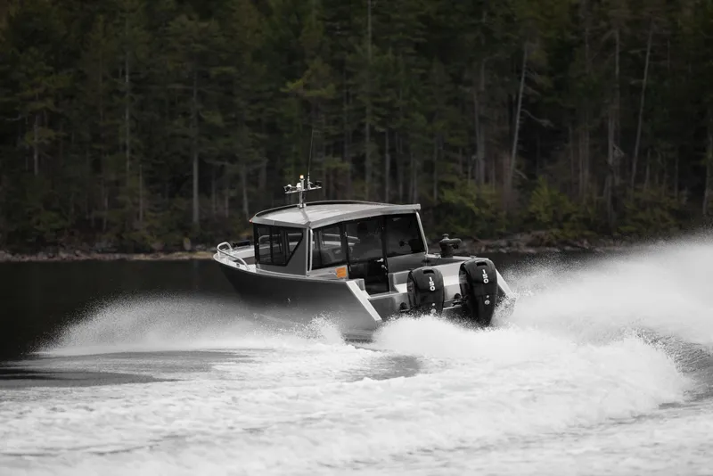 Slide: The Image of 2025 Jasper Marine Defender 22 boat speeding on a lake with forest background. - 17