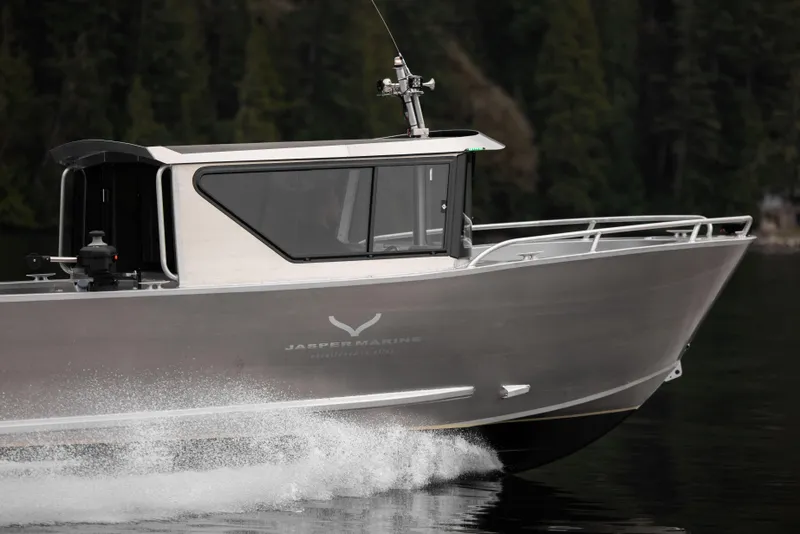 Slide: The Image of 2025 Jasper Marine Defender 22 boat cruising on a lake with forest background. - 19