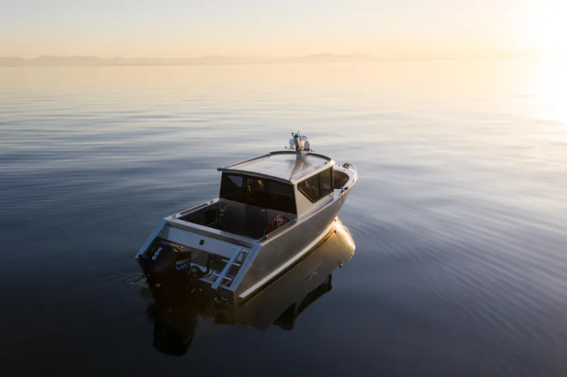 Slide: The Image of 2025 Jasper Marine Defender 22 boat on calm water at sunset. - 3
