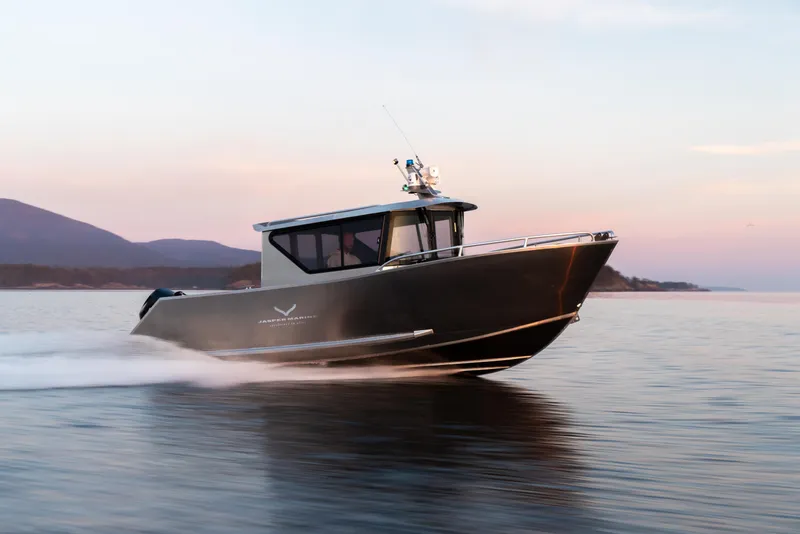 Slide: The Image of 2025 Jasper Marine Defender 22 boat cruising on a calm lake at sunset. - 14