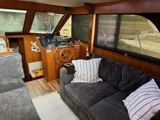 Slide: The Image of 1989 Jefferson Motoryacht interior with helm, grey sofa, and striped pillows. - 10