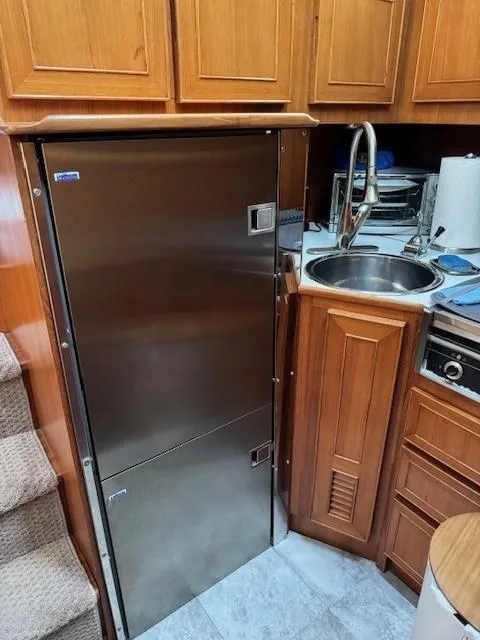 Slide: The Image of 1989 Jefferson Motoryacht kitchen with stainless steel fridge, sink, and wooden cabinets. - 16