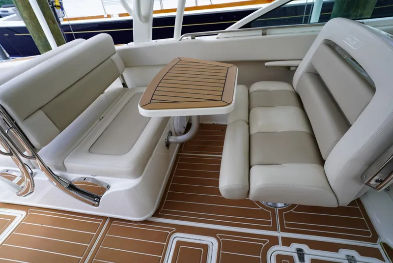 Slide: The Image of 2016 Boston Whaler 320 Vantage boat interior with cushioned seating and wooden table. - 10