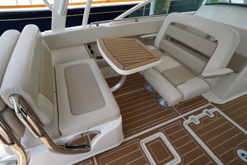 Slide: The Image of 2016 Boston Whaler 320 Vantage boat interior with beige seating and wooden table. - 11