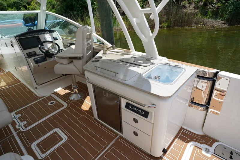 Slide: The Image of 2016 Boston Whaler 320 Vantage boat interior with helm, sink, and storage. - 15
