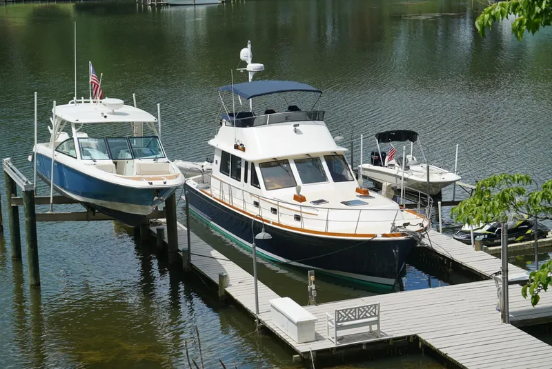 Slide: The Image of 2016 Boston Whaler 320 Vantage docked beside a larger boat on a calm lake. - 26